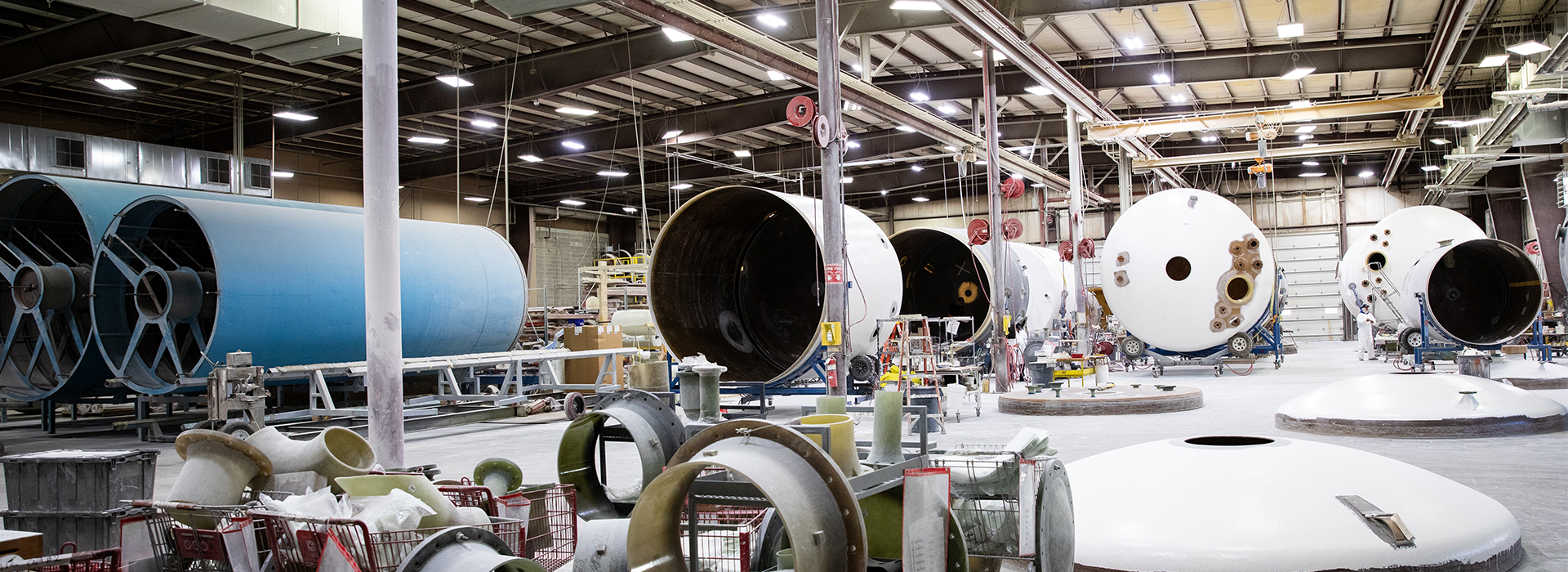 Factory setting of in-progress fiberglass tanks in various sizes.